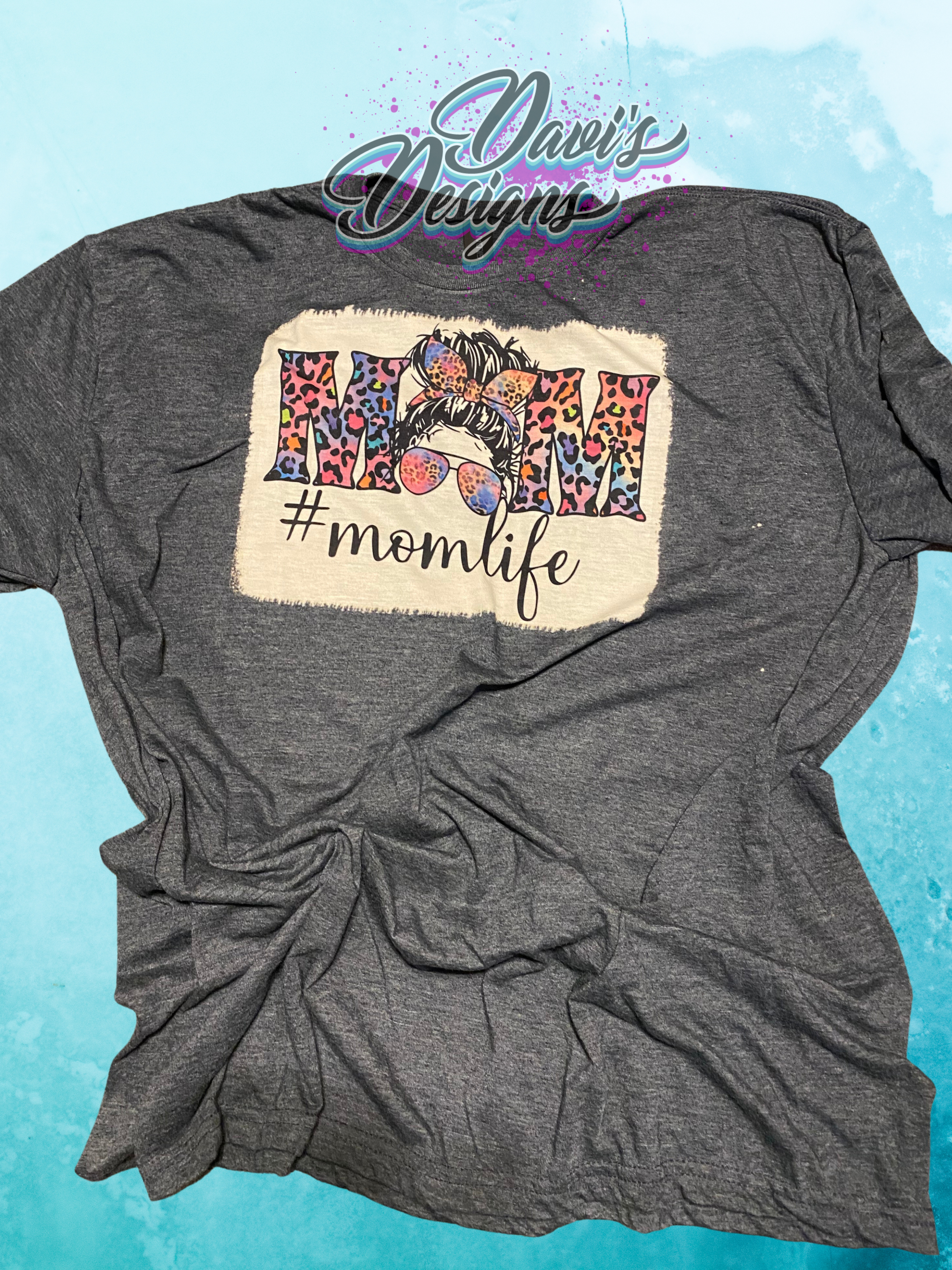 Dark Heather bleach patterned tee with bright colored leopard print Messy Bun saying Momlife.